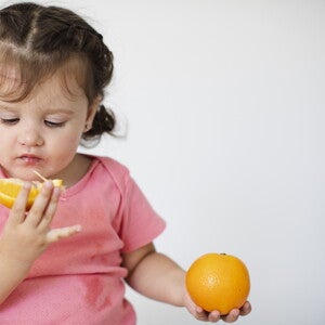 toddler looking at a slice of orange