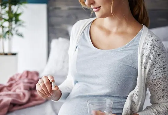 Targeting Obesity Risk in Early Life: The Role of Maternal Nutritional Supplementation pregnant woman holding a capsule and a glass